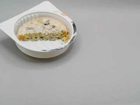 Spoiled moldy cheese left in plastic packaging on light background with cop.. Stock Photos