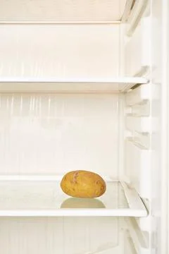 Spoiled potato is on the shelf of an empty refrigerator Stock Photos