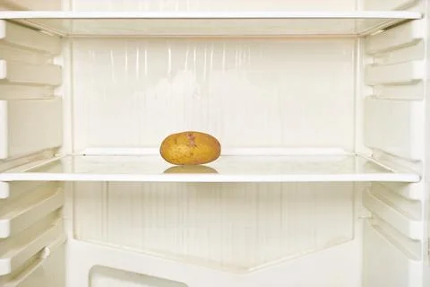 Spoiled potato is on the shelf of an empty refrigerator Stock Photos