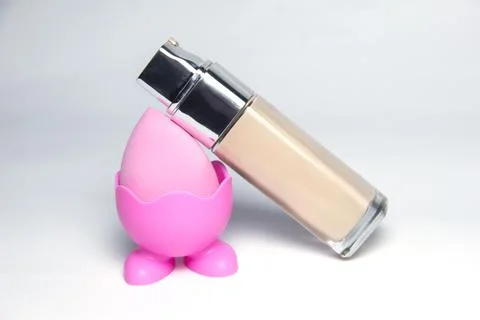 Sponge for the base. Pink sponge for makeup. Bottles of foundation Stock Photos