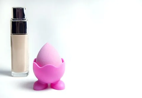 Sponge for the base. Pink sponge for makeup. Bottles of foundation Stock Photos