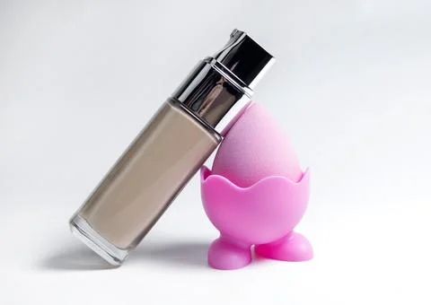 Sponge for the base. Pink sponge for makeup. Bottles of foundation Stock Photos