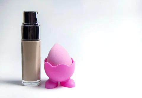 Sponge for the base. Pink sponge for makeup. Bottles of foundation Stock Photos