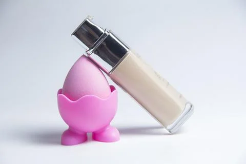 Sponge for the base. Pink sponge for makeup. Bottles of foundation Foto stock
