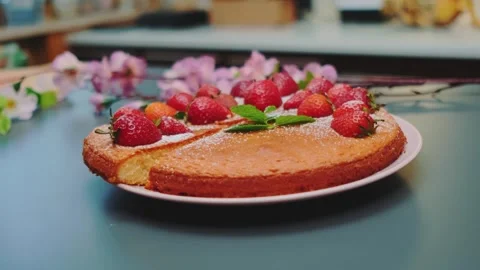 Sponge cake topped with fresh strawberries and mint leaves on kitchen counter Stock Footage 342867287