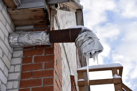 Spontaneous ventilation pipe in a house with icicles and ice in winter. The.. Stock Photos