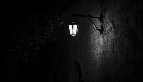 Spooky black and white alley with a lit street lamp Stock Photos