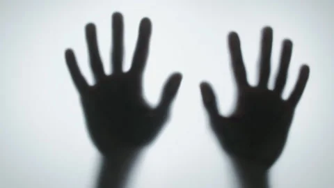 Spooky black silhouette of two hands sliding down a frosted glass surface.  Stock Footage 327158431