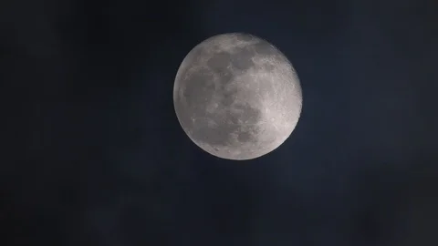 Spooky dark clouds pass the moon at night nearly in full phase seen by refractor Stock Footage 123217709