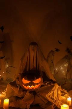 Spooky ghost holding glowing Jack o lantern pumpkin on background of spider.. Stock Photos
