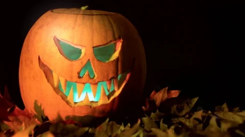 Spooky iluminated Jack OLantern halloween pumpkin on dry leaves Stock Footage 117936140