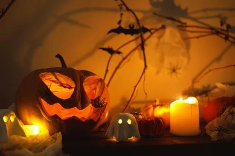 Spooky Jack o lantern pumpkin, glowing ghosts, spiders and bats in evening... Stock Photos