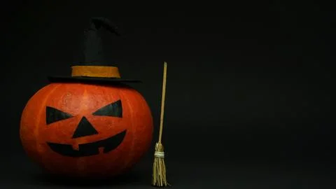 Spooky Jack-o-Lantern Pumpkin in Witch Hat with Broom on Dark Background Stock Photos