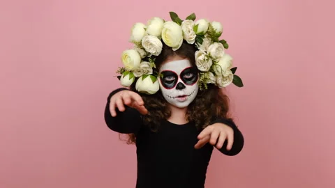 Spooky little girl with Halloween makeup flowers wreath hands raised, scares Stock Footage