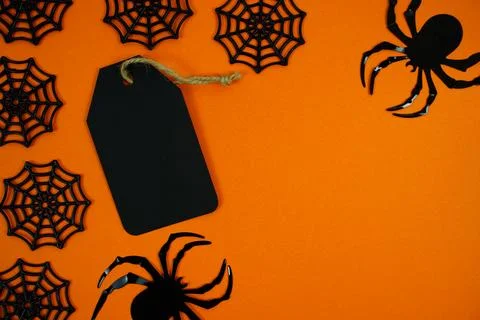 Spooky orange background featuring a black gift tag, spider webs, and a cre.. Stock Photos