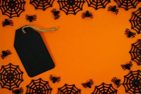 Spooky orange background featuring a black gift tag, spider webs, and a cre.. Stock Photos