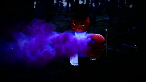 Spooky Pumpkin Headed Man Holding A Huge Pumpkin With Blue Smoke In The Forest Stock Footage 141258013