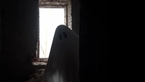 Spooky white figure peeks from behind wall, surrounding room left in darkness Stock Footage 320246672