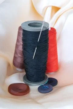 Spool of black thread with a needle and buttons Stock Photos