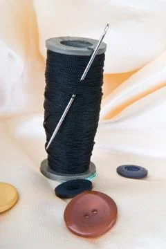 Spool of black thread with a needle and buttons Stock Photos