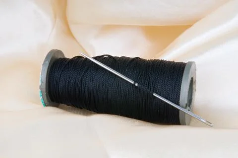 Spool of black thread with a needle and buttons Foto stock