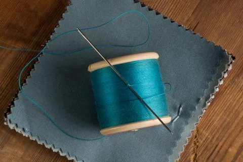 Spool of Blue Thread and Needle on Fabric Swatches Stock Photos