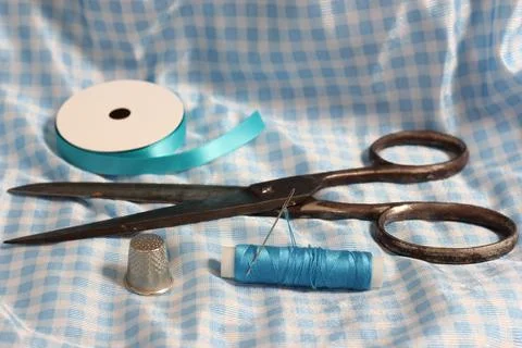 Spool of Blue Thread, Thimble and Needle on Blue and White Fabric Stock Photos