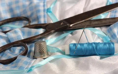 Spool of Blue Thread, Thimble and Needle on Blue and White Fabric Stock Photos
