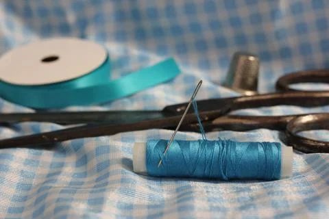 Spool of Blue Thread, Thimble and Needle on Blue and White Fabric Stock Photos