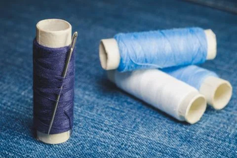 A spool of blue threads with a sewing needle Stock Photos
