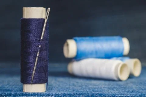 A spool of blue threads with a sewing needle Stock Photos