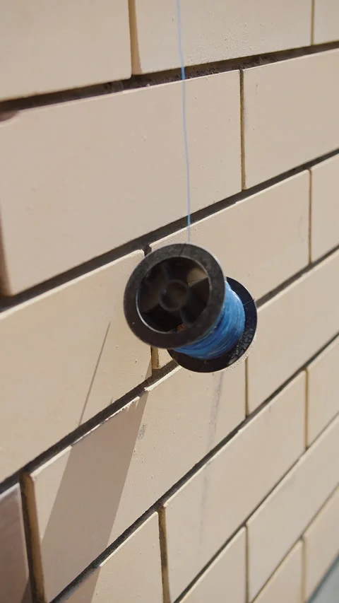 Spool with blue wire hanging on tiled wall Stock Footage 310953594
