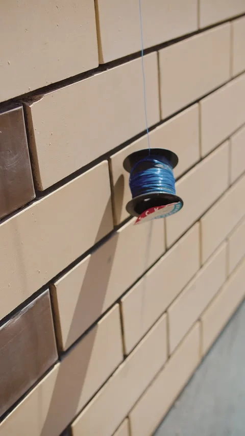 Spool of blue wire hanging on tiled exterior wall Stock Footage 310953651