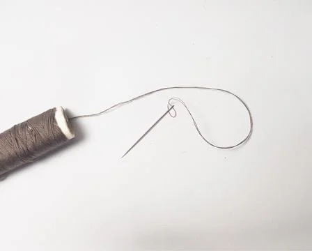 A spool of brown sewing thread with a needle next to it isolated on a white.. Stock Photos