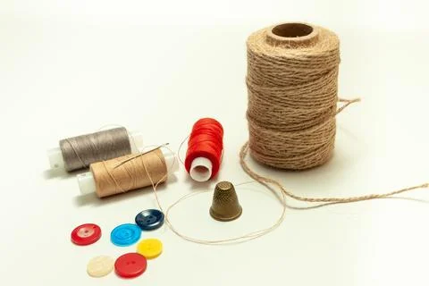 Spool of coarse thread and spool of colored thread, buttons and thimble on .. Stock Photos