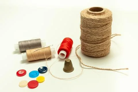 Spool of coarse thread and spool of colored thread, buttons and thimble on .. Stock Photos