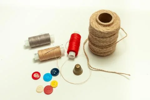 Spool of coarse thread and spool of colored thread, buttons and thimble on .. Stock Photos