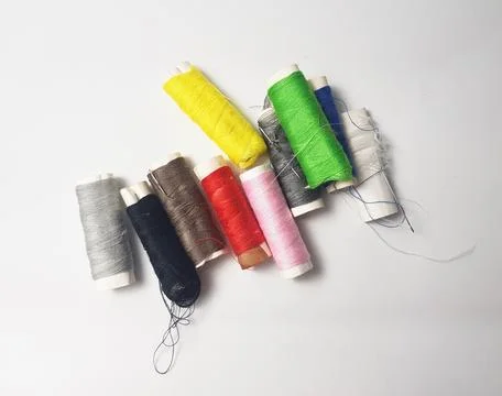 A spool of colorful sewing thread with a needle on it isolated on a white b.. Stock Photos