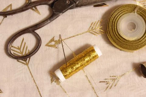 Spool of Gold Thread and Scissors With Thimble on Metallic Fabric Stock Photos