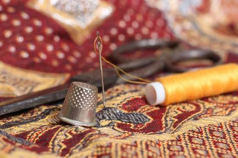 Spool of golden thread with a needle and thimble on a vintage middle eastern fab Stock Photos