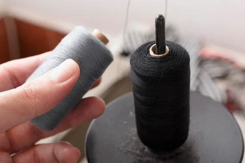 Spool of Gray Thread in Hand and Black Thread on Pin Stock Photos