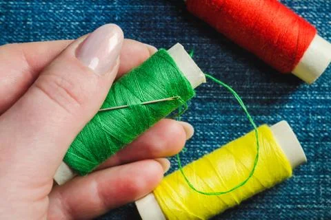Spool of green sewing thread and a needle in a female hand Stock Photos