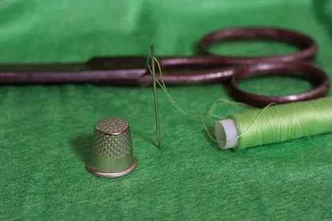 Spool of Green Thread, Thimble, and Needle on Green Fabric Close up Foto stock