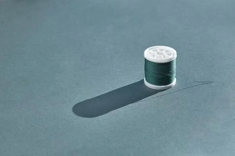 A spool of high-quality sewing thread in bright emerald color stands on a har Stock Photos