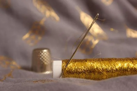 Spool of Metallic Gold Thread on Gray and Gold Fabric Stock Photos