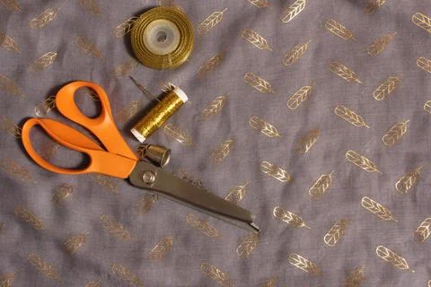 Spool of Metallic Gold Thread on Gray and Gold Chiffon Fabric Stock Photos