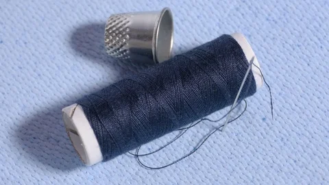 Spool with needle and thimble on cloth Stock Footage 70748249