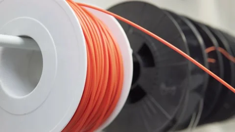 A spool of orange 3D printing filament spinning Stock Footage 140737929