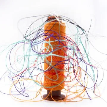 Spool of orange thread and colorful string on a white background Stock Photos