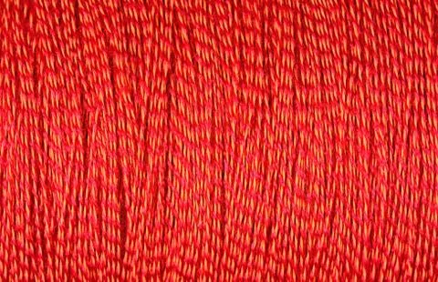 Spool of orange thread macro background Foto stock
